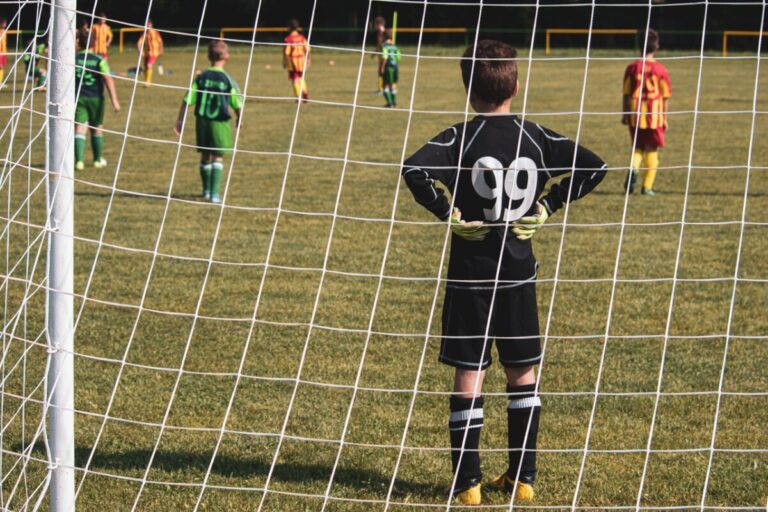 Children playing football, with goalkeeper in the foreground. Photo: Pexels.com