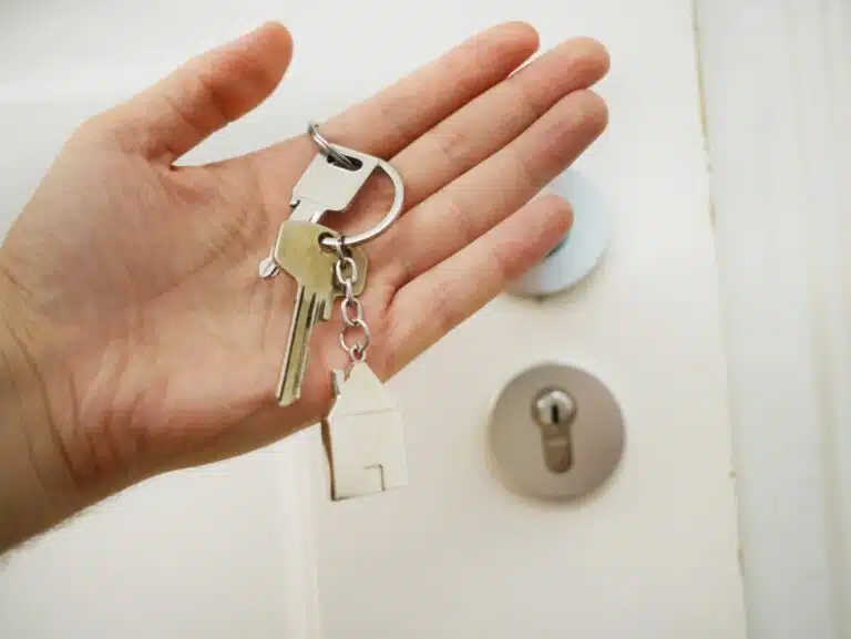 House keys in a hand, by a front door.