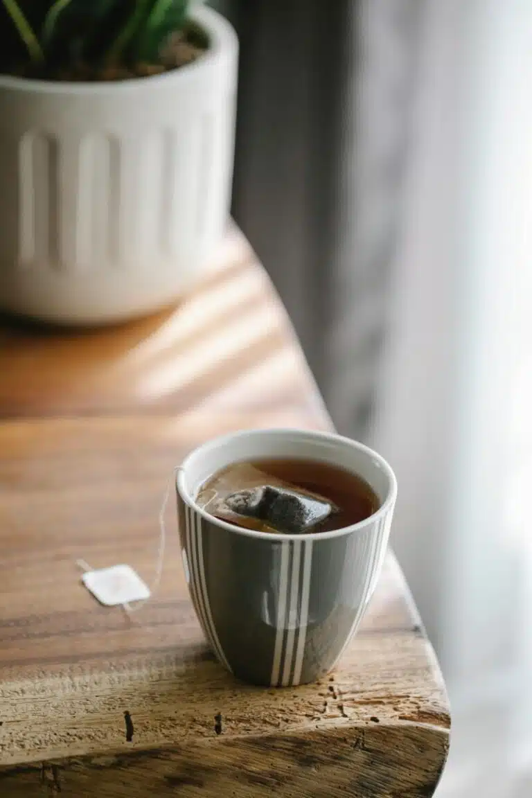 Cup of tea on a table, with a tea bag on a string.