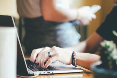 Remote working - a woman with a ring on one finger and three wristbands types at a laptop. Photo: pxhere.com