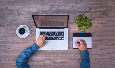 Image looking down at a man working on a laptop and a tablet by Lukas Bieri from Pixabay