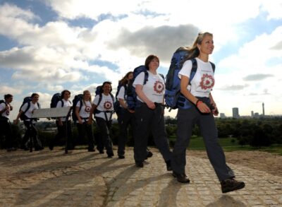 Line of woman with rucksacks and identical t-shirts marching to the right