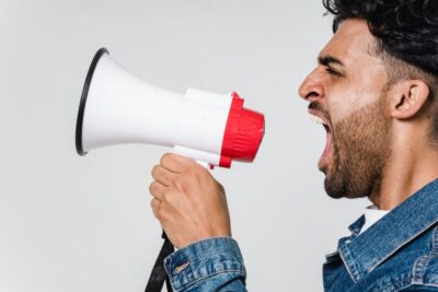 Man in denim jacket shouting into a loud-hailer. Photo: Pexels.com