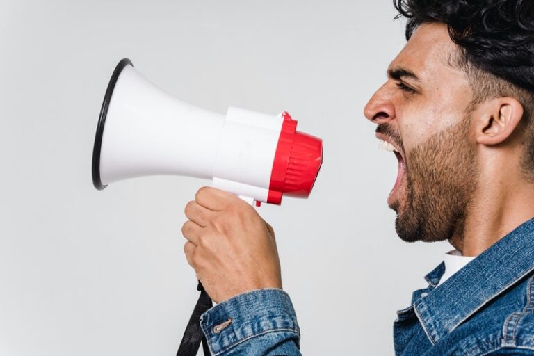 Man in denim jacket shouting into a loud-hailer. Photo: Pexels.com