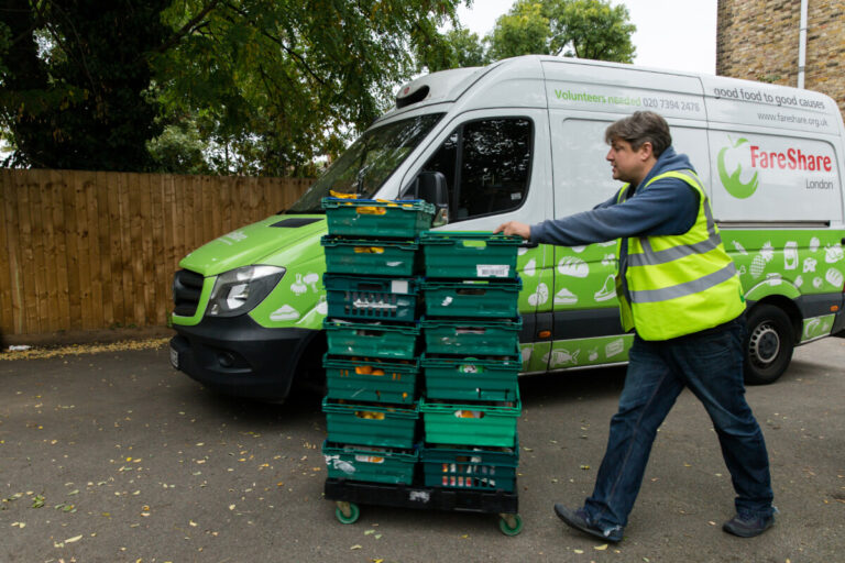 Fareshare volunteer delivering donated food beside a Fareshare van