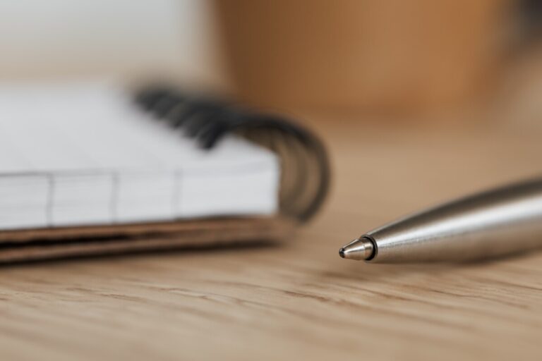 the corner of a ringbound notebook and a silver pen