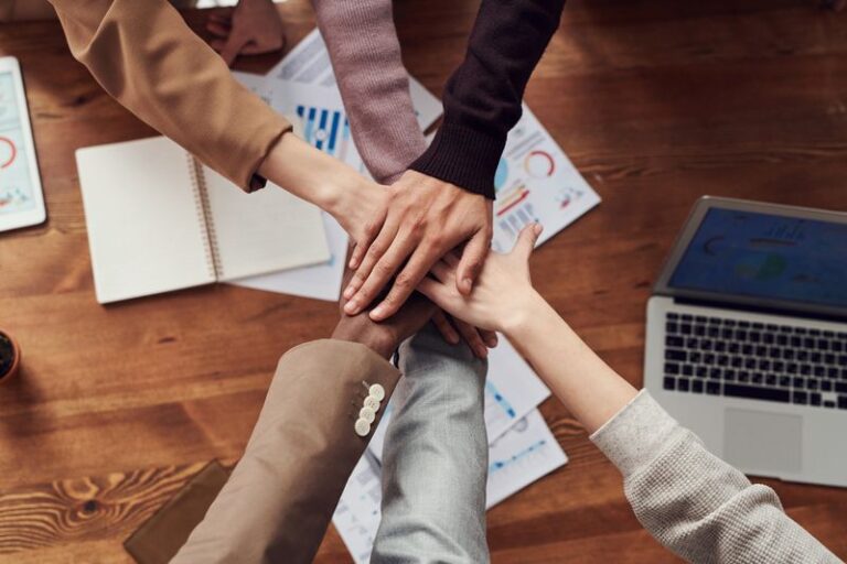 People joining hands over a desk