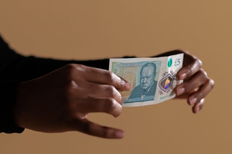 A woman's hands holding a £5 note