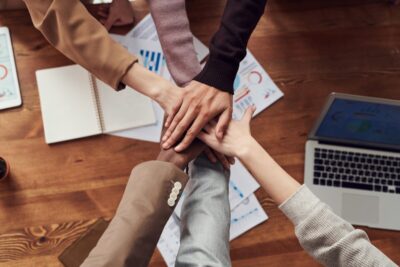 hands meeting over a desk symbolising teamwork