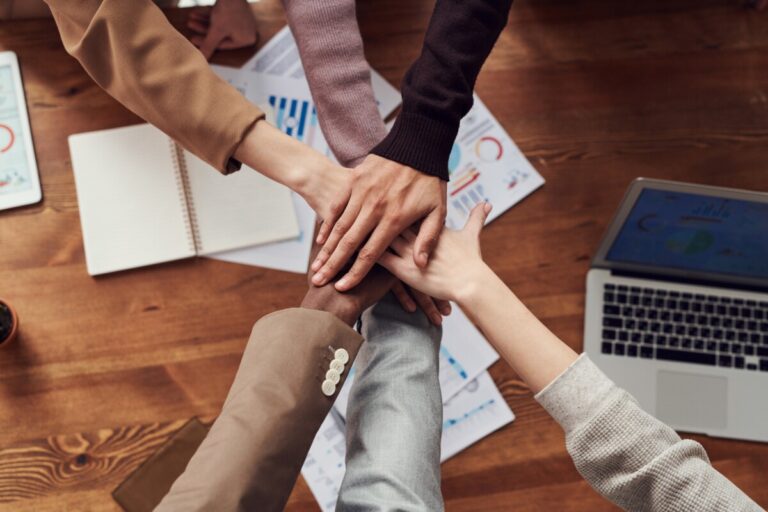 hands meeting over a desk symbolising teamwork