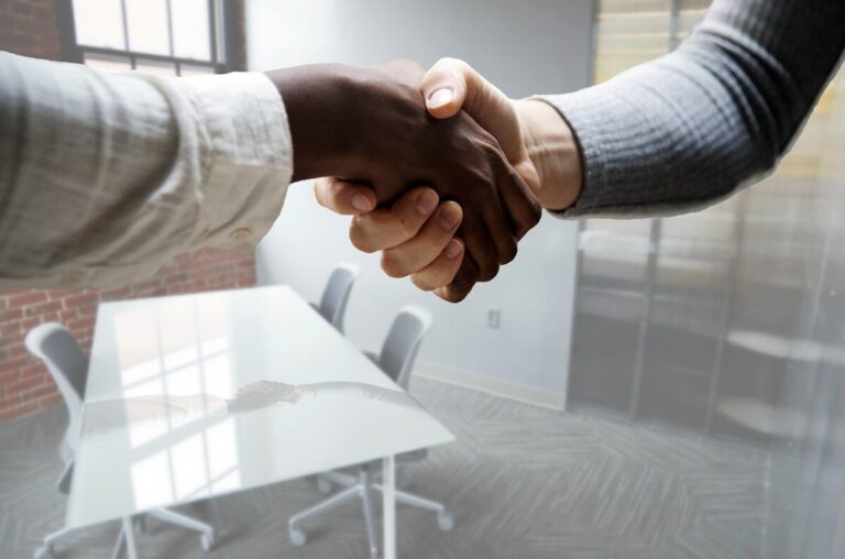 Two women shaking hands in a white office