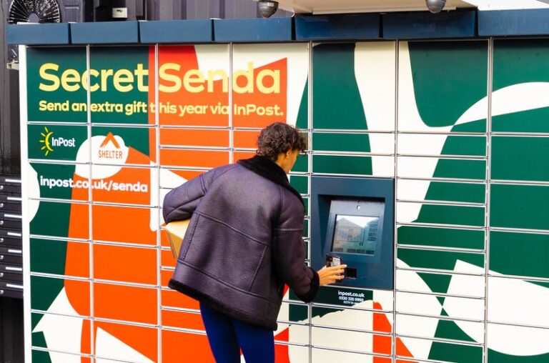 A woman keys in a code to open an InPost locker with a box under her arm