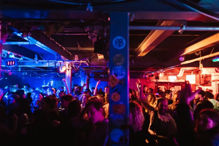 People dance in crowded dimly lit room