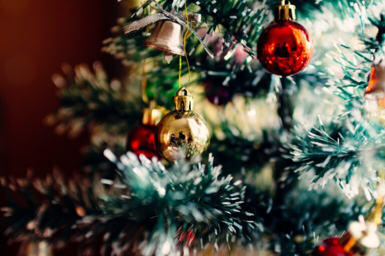 A close up of red and gold baubles on a white frosted christmas tree