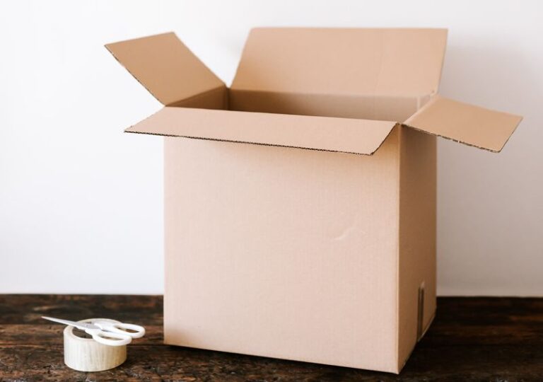 a cardboard box next to a roll of tape and scissors