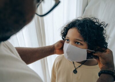 A man helps his son put his face mask on