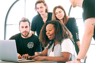 Team gather around a computer. Photo: Pexels.com