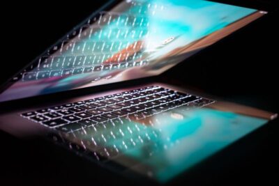 Laptop half-open in a dark room. Photo: Pexels