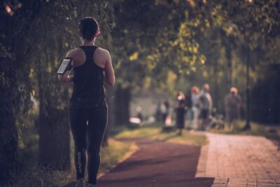 A woman running on a path through sunlit trees