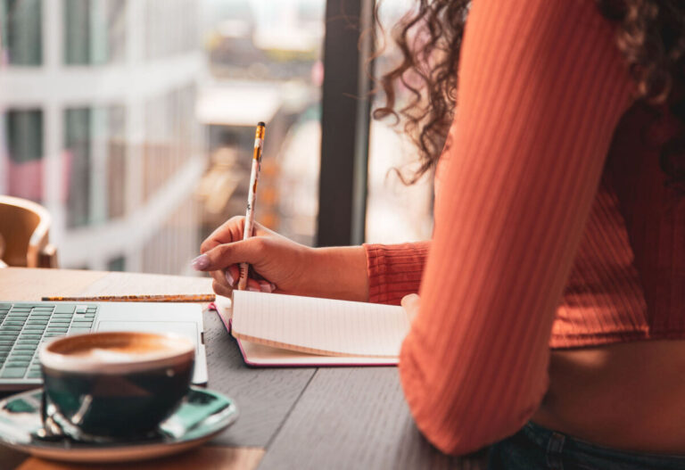 a woman works at a desk with a coffee by her side