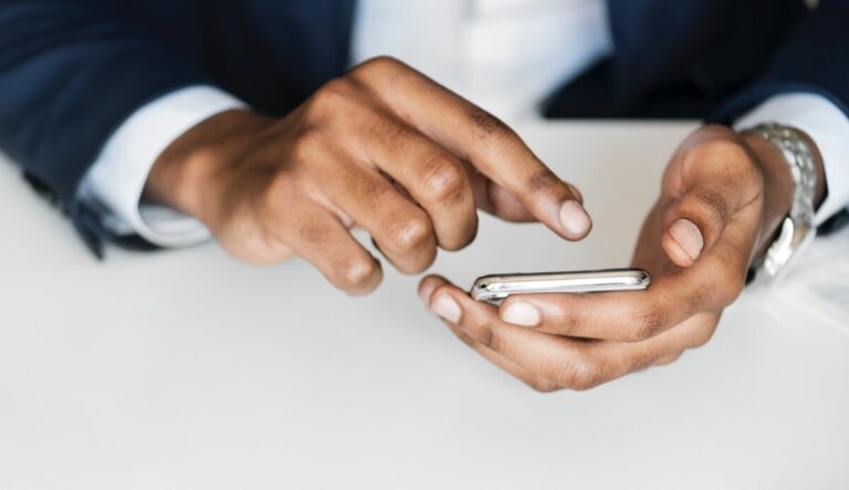 A man's hands holding his phone and about to touch the screen