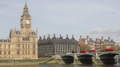 House of Commons with red London buses going over the bridgfe