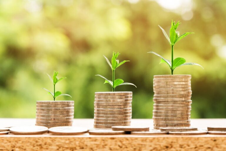 three piles of coins with green shoots on the top