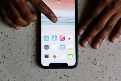 A finger reaches for the Instagram icon on a phone. By Cottonbro on Pexels