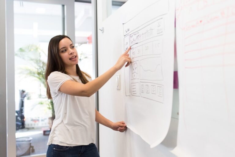 A woman points to a chart on a whiteboard. By WOCINTECH on Nappy.co