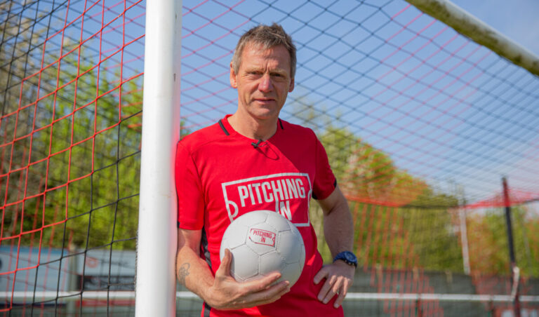 Footballer Stuart Pearce leans on a goal post holding a football