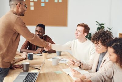 two men shake hands over an office desk. By Fauxels on Pexels