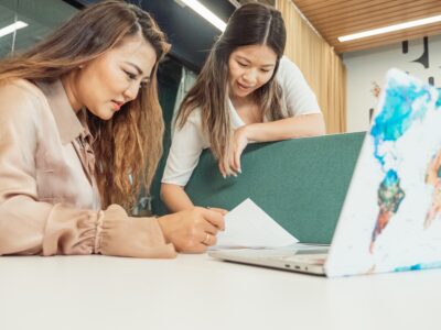 Two women look at documents in an office. Image by Kindel Media on Pexels