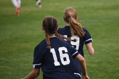 The back of two girls playing football. By Matthew Warren on Pixabay