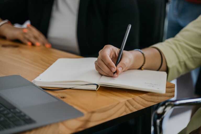 A woman's hand writes in a notebook