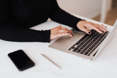 A woman in a black top types on a laptop