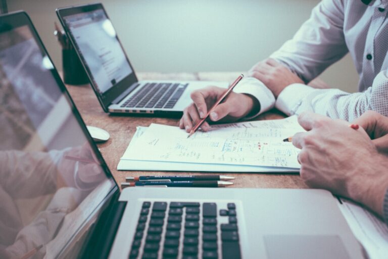 Two men work in front of their laptops. By Scott Graham on Unsplash