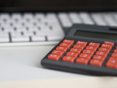 A calculator rests against a computer keyboard. By Edar on Pixabay