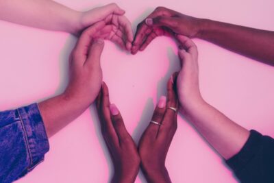 Different peoples hands combine to make a heart shape. By ATC comm on pexels