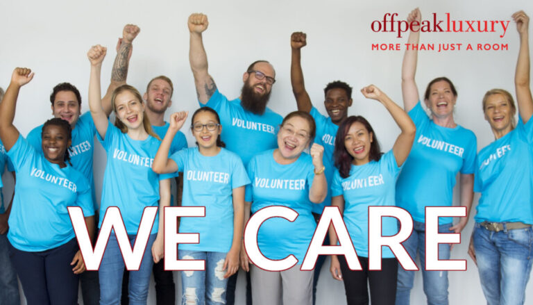 WE CARE team photo of people dressed in blue t shirts that say 'volunteer' with arms raised