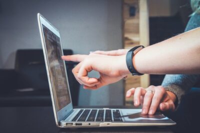 A hand points to something on a laptop screen. By John Schnobrich on Unsplash