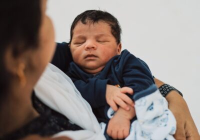 An Indian lady cradles a baby dressed in blue. By Ben Moses on Pexels