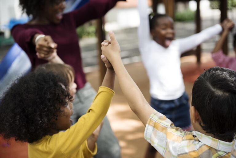 Young children sing and dance in a circle holding hands