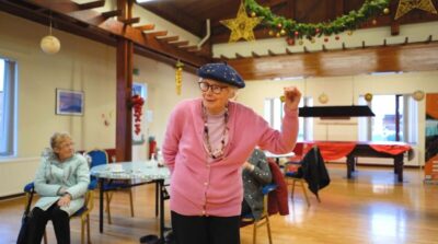 An older woman in a hat and a pink cardigan dances – at Glasgow's Golden Generation