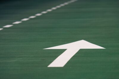 Up arrow on a green road or runway. Photo by Jan van der Wolf: https://www.pexels.com/photo/arrow-on-the-road-7173266/