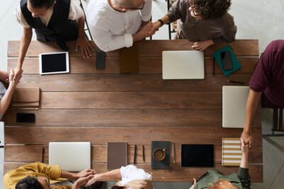 Arial shot of people shaking hands around a table. By Fauxels on Pexels