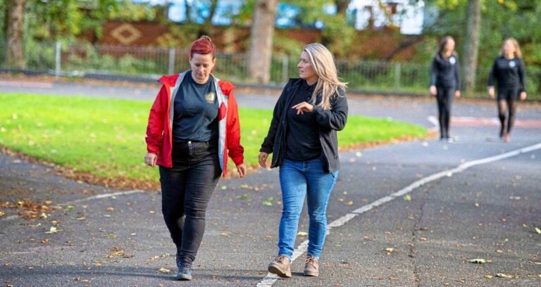 Two women talk as they walk along a path