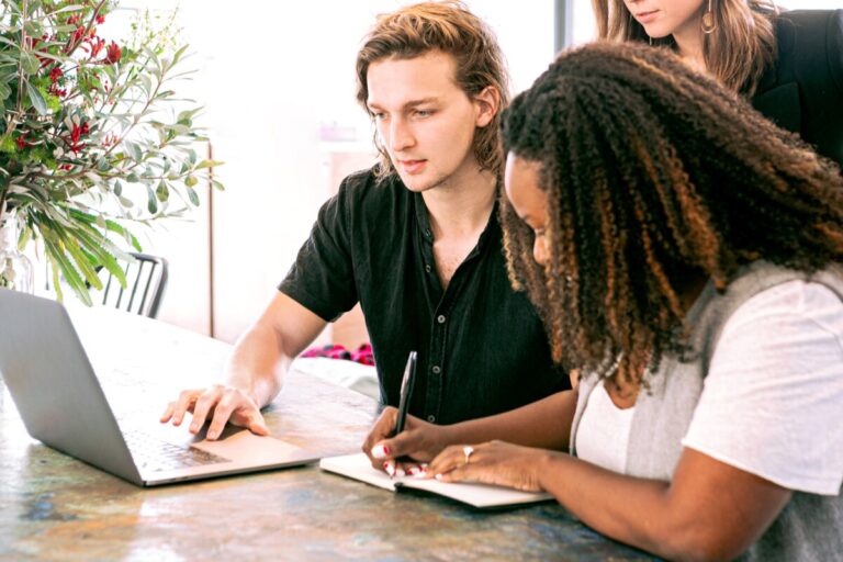 three people sit by a computer. By canva studios on Pexels