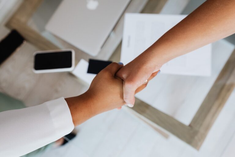 A photo looking down on two women shaking hands. By Karoline Grabowska on Pexels