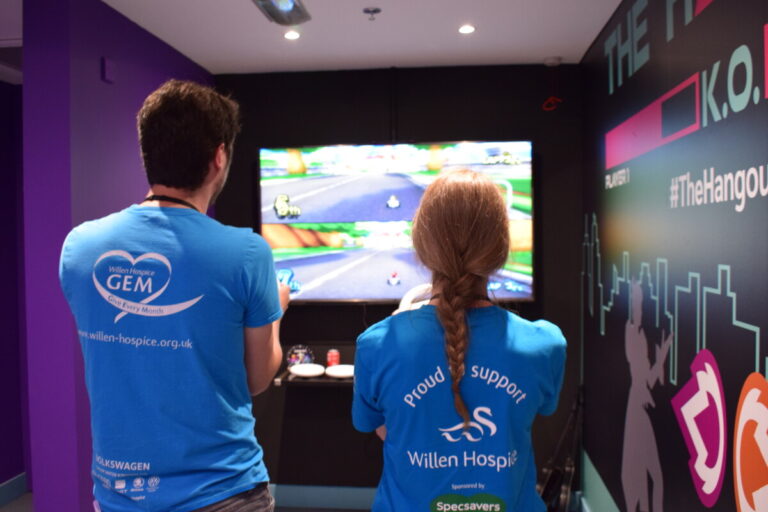 Staff in blue Willen Hospice t shirts play a game at Willen Hospice's new gaming shop, The Hangout