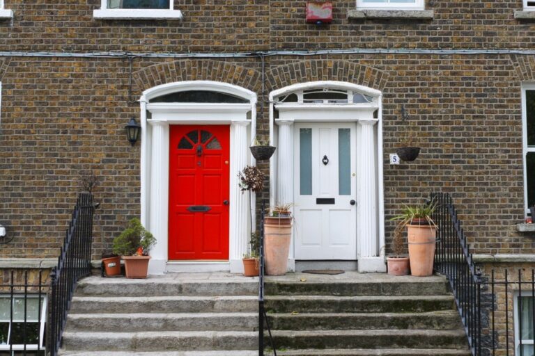 two front doors on houses, side by side, one is red, the other is white, and steps lead up to them. By Ptrabattoni on pixabay